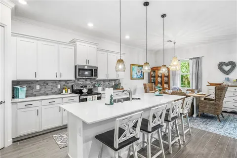 a kitchen with stainless steel appliances kitchen island granite countertop a sink a stove a dining table and chairs