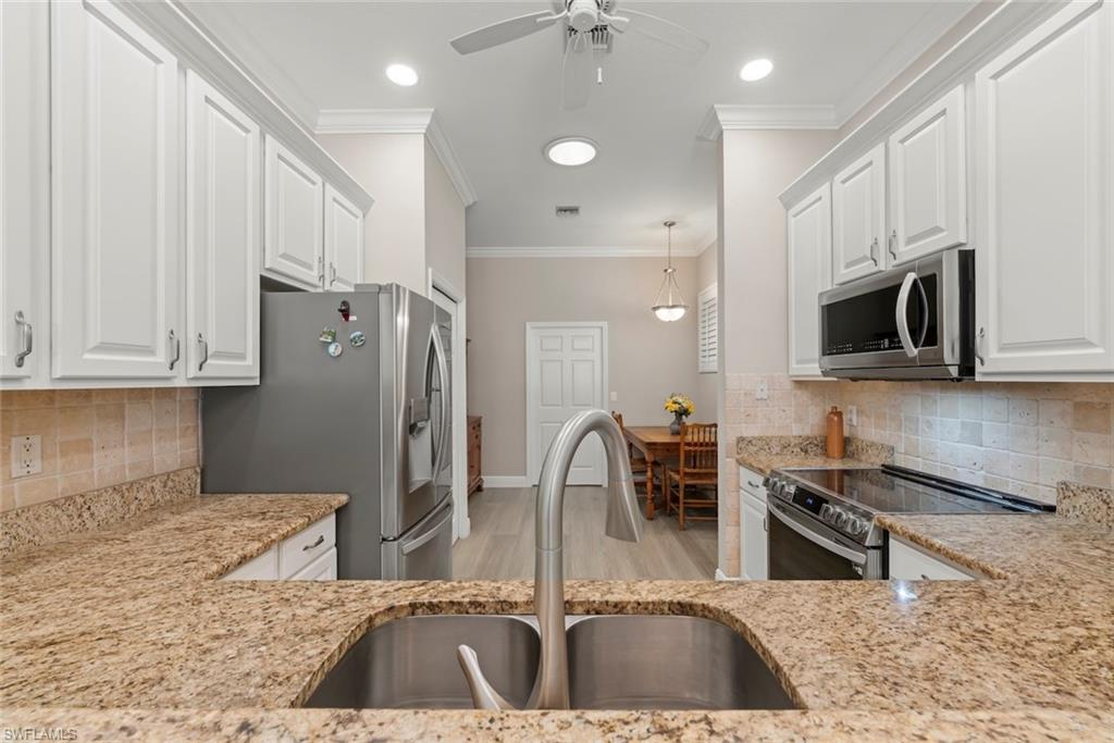 3653 Periwinkle Way, Unit 127 Naples, FL 34114 - Photo 20 of 44 a kitchen with stainless steel appliances granite countertop a sink a stove and a microwave oven with cabinets