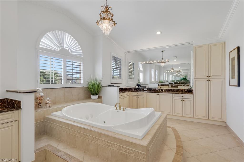 1859 Ivory Cane Point Naples, FL 34119 - Photo 31 of 50 Full bathroom with vanity, a chandelier, a tub with jets, crown molding, and light tile patterned flooring