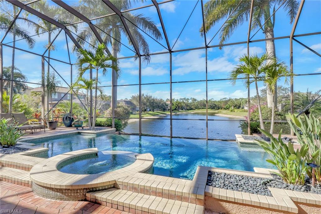 1859 Ivory Cane Point Naples, FL 34119 - Photo 40 of 50 View of pool featuring a pool with connected hot tub, glass enclosure, a water view, a sunroom, and a patio area