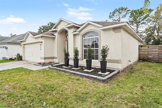 a view of a white house with a small yard and plants