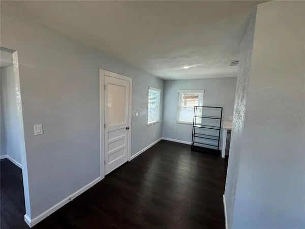 an empty room with wooden floor closet and windows