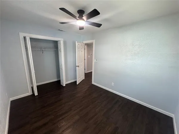 an empty room with wooden floor and a ceiling fan