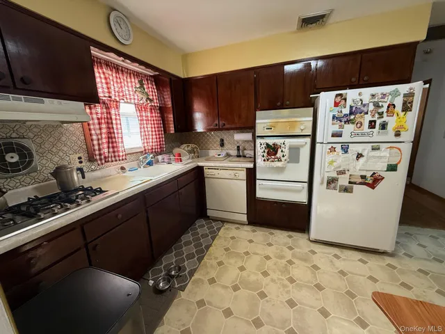 a kitchen with stainless steel appliances a refrigerator a sink a stove a microwave and wooden cabinets
