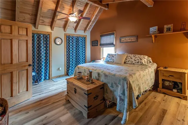 a bedroom with a bed next to a window with wooden floor