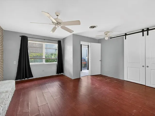 an empty room with wooden floor fan and windows