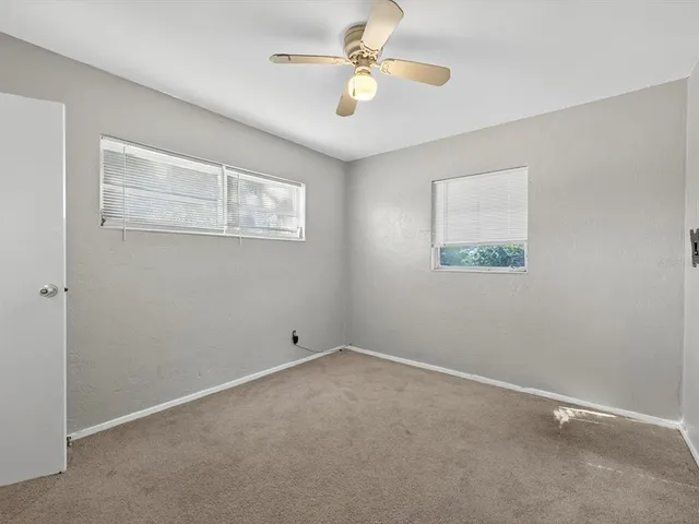 an empty room with a window and a fan