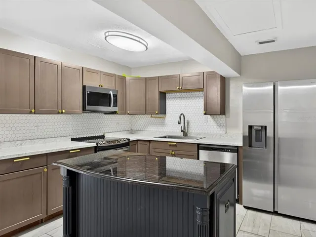 a kitchen with kitchen island a sink appliances and cabinets