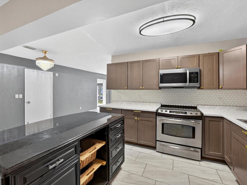 1068 Peter Road Daytona Beach, FL 32114 - Photo 7 of 37 a kitchen with stainless steel appliances granite countertop a stove and a microwave