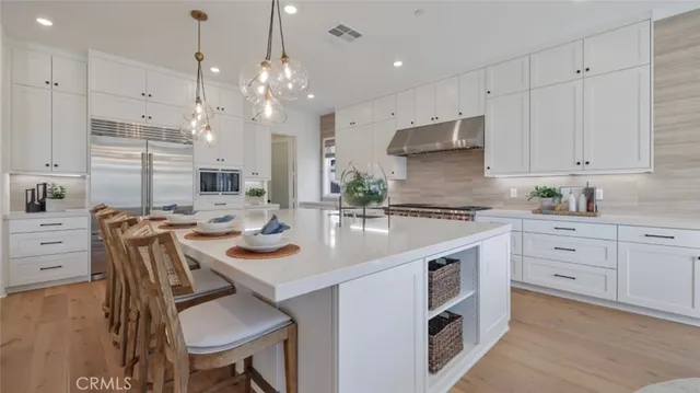 a kitchen with kitchen island granite countertop a sink a stove refrigerator and white cabinets with wooden floor