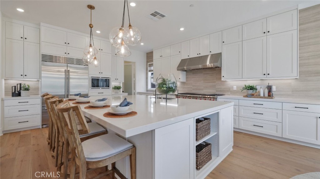 a kitchen with kitchen island granite countertop a sink a stove refrigerator and white cabinets with wooden floor