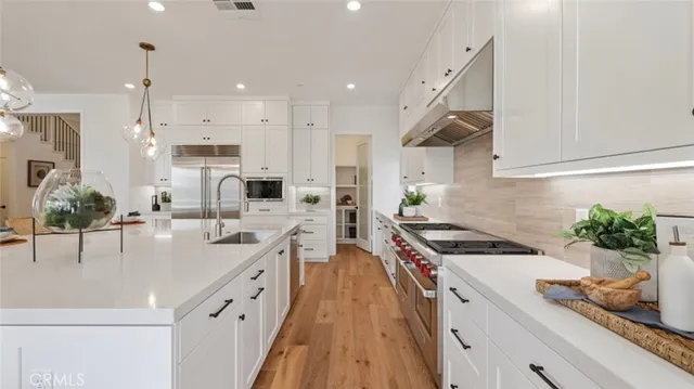a kitchen with stainless steel appliances a sink a stove and a wooden floors