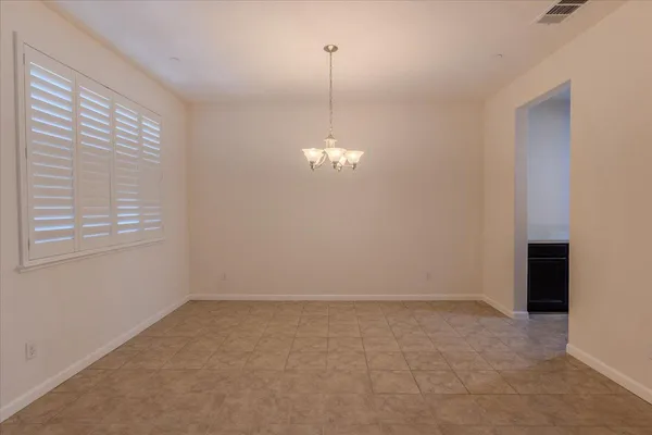 an empty room with chandelier fan and windows