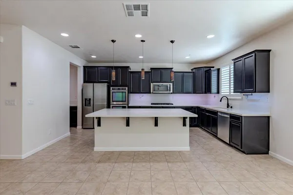 a living room with stainless steel appliances kitchen island granite countertop a sink and cabinets