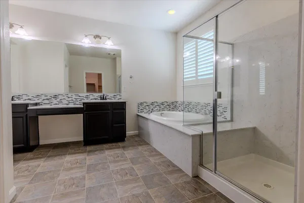 a spacious bathroom with a granite countertop sink a mirror and a bathtub