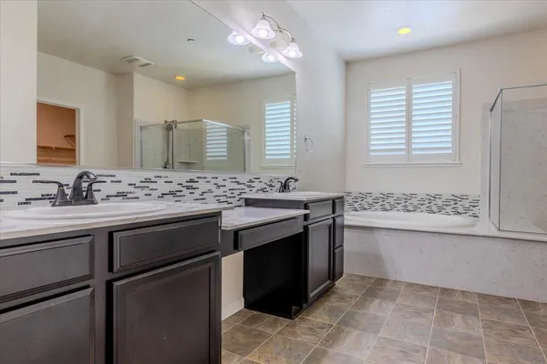 a bathroom with a sink vanity granite tub and a mirror