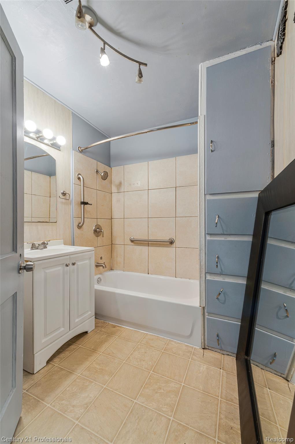 238 Richter Street River Rouge, MI 48218 - Photo 23 of 33 Bathroom featuring a white vanity with a single basin, tiled flooring, a bathtub with a tiled surround, and integrated wall cabinetry