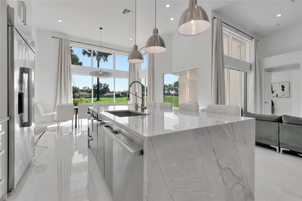 a large kitchen with granite countertop a large counter top a sink and stainless steel appliances