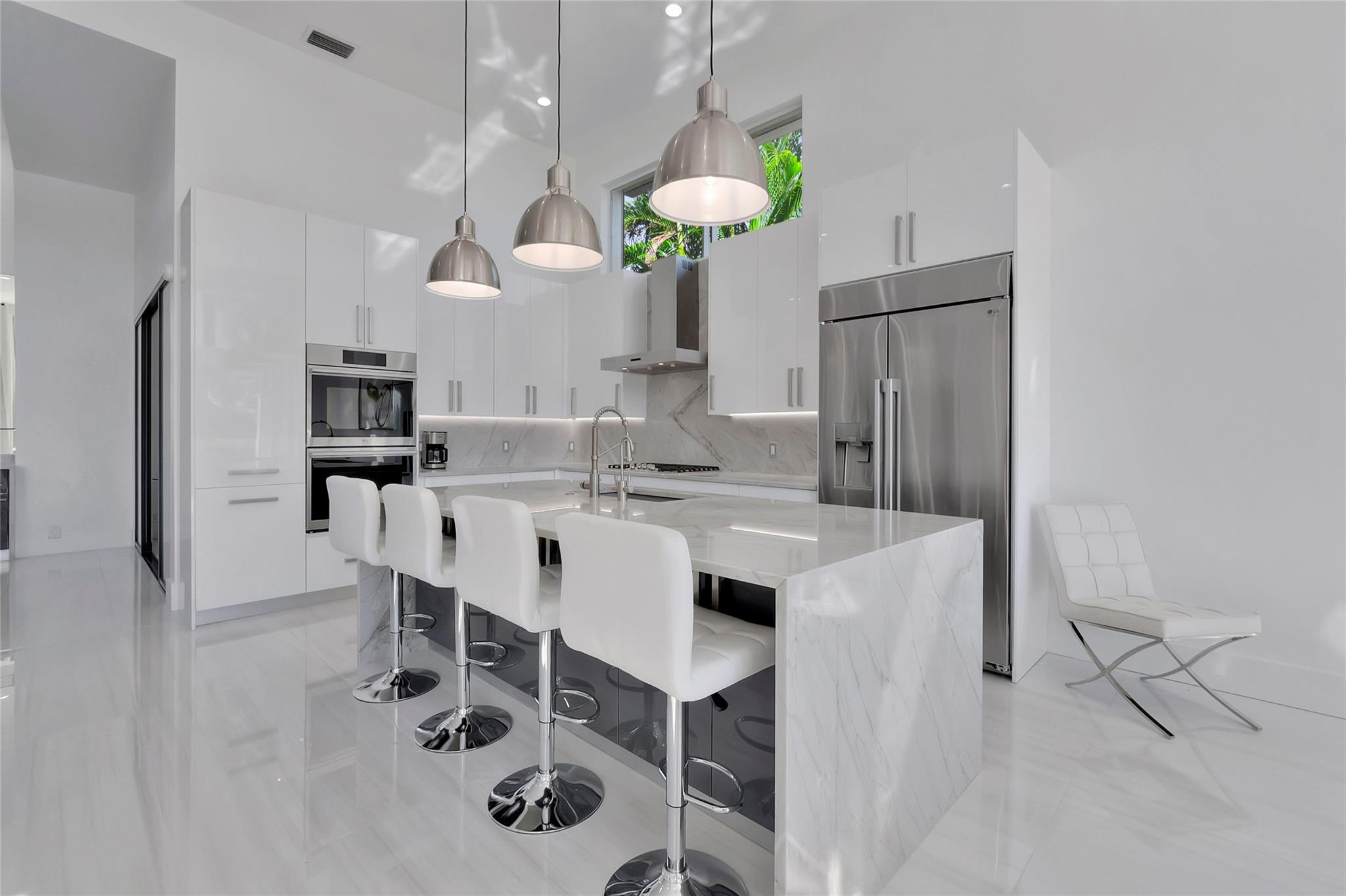 4088 Briarcliff Circle Boca Raton, FL 33496 - Photo 2 of 36 a kitchen with stainless steel appliances kitchen island granite countertop a refrigerator a stove a microwave and a dining table with wooden floor