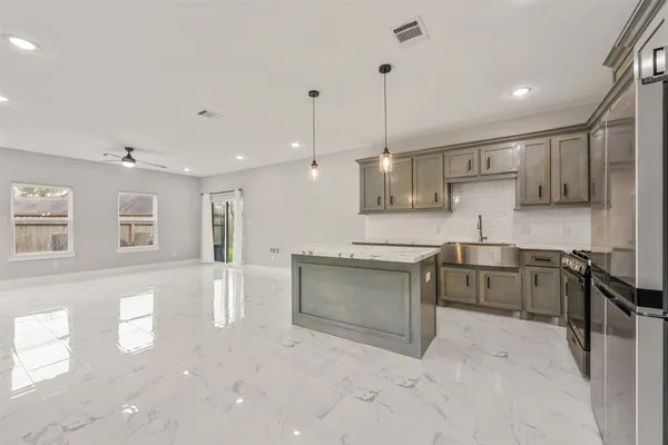 a large kitchen with stainless steel appliances kitchen island granite countertop a sink and cabinets