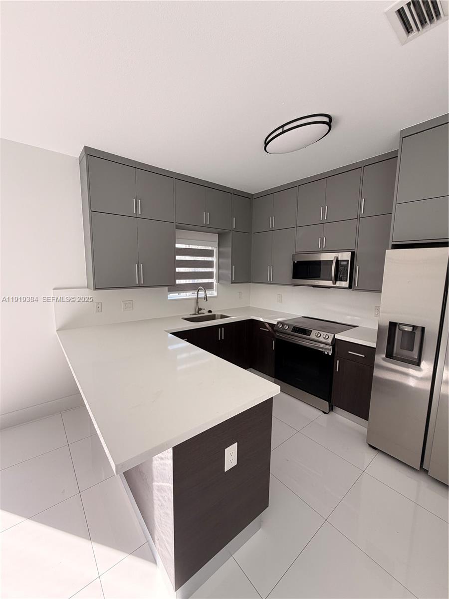 17334 Southwest 303rd Street Homestead, FL 33030 - Photo 18 of 34 a kitchen with stainless steel appliances a refrigerator sink and stove