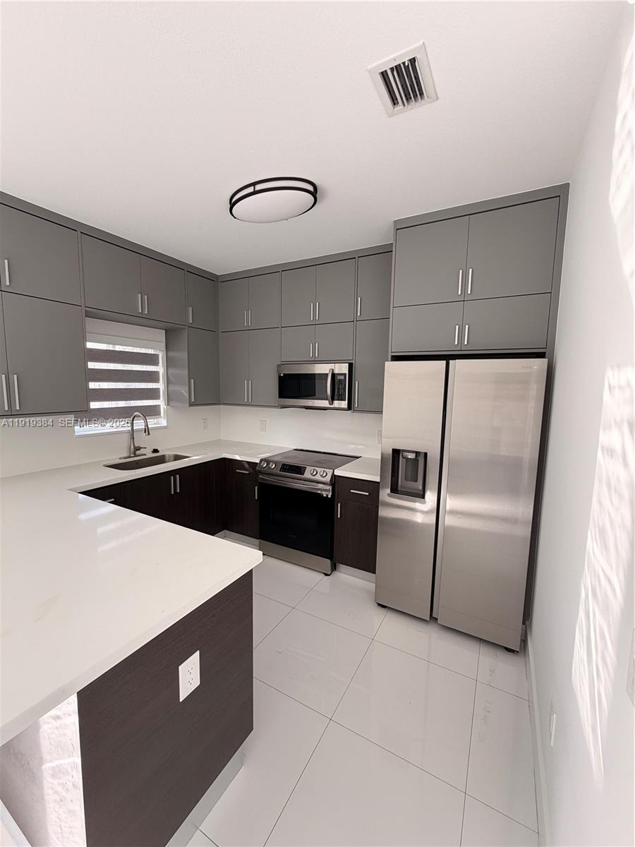 17334 Southwest 303rd Street Homestead, FL 33030 - Photo 19 of 34 a kitchen with stainless steel appliances a refrigerator sink and stove