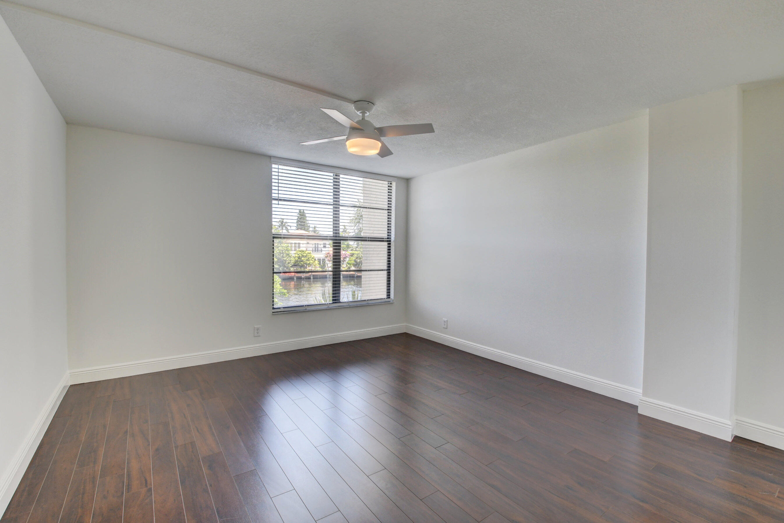 18 Royal Palm Way, Unit 202 Boca Raton, FL 33432 - Photo 19 of 51 an empty room with wooden floor chandelier fan and windows