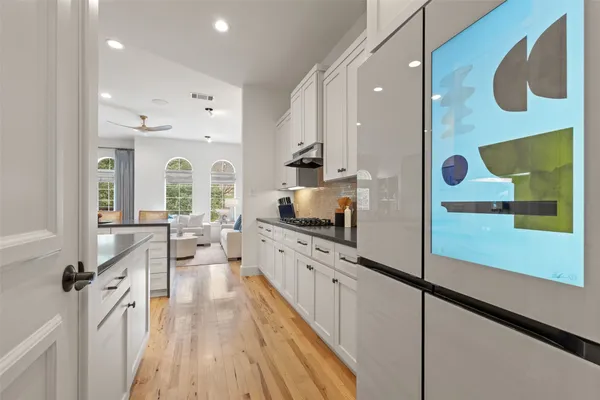 a large kitchen with stainless steel appliances a large counter top a stove and a wooden floors