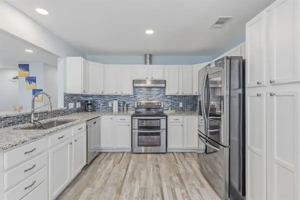 a kitchen with granite countertop a sink stainless steel appliances and cabinets