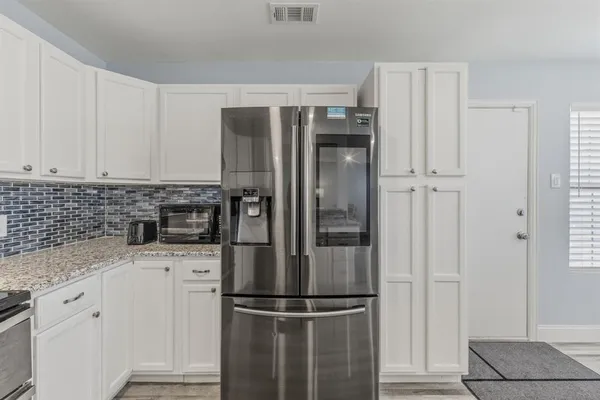 a kitchen with stainless steel appliances granite countertop a refrigerator and white cabinets