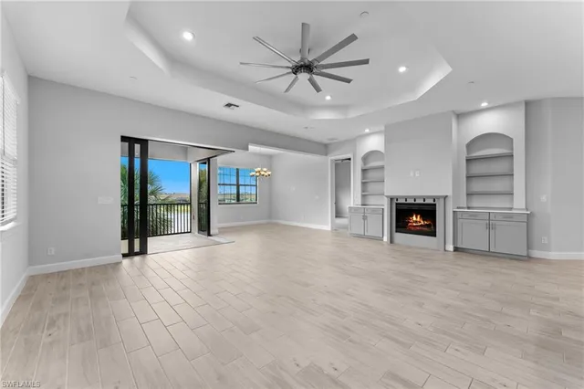 an empty room with windows fireplace and a ceiling fan