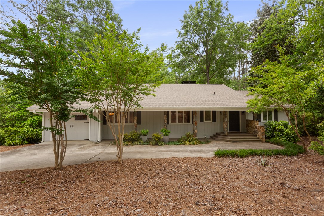 This ranch-style home features a classic design with natural stone accents and lush greenery.
