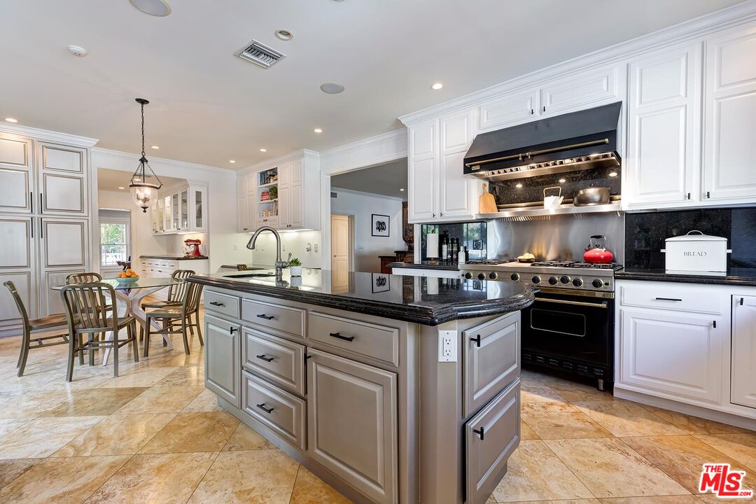 3827 Castle View Road Agoura Hills, CA 91301 - Photo 31 of 74 a kitchen with stainless steel appliances granite countertop a stove top oven a sink a dining table and chairs with wooden floor
