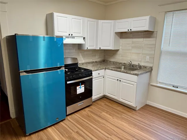 a kitchen with granite countertop a refrigerator and a stove top oven