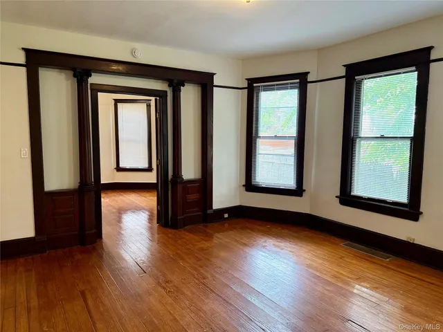 a view of an empty room with wooden floor and a window