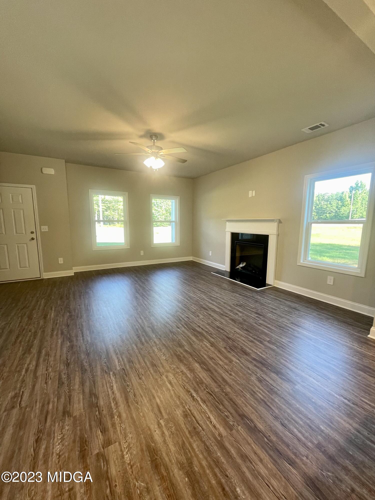 23 Strickland Loop Forsyth, GA 31029 - Photo 2 of 9 an empty room with wooden floor and windows