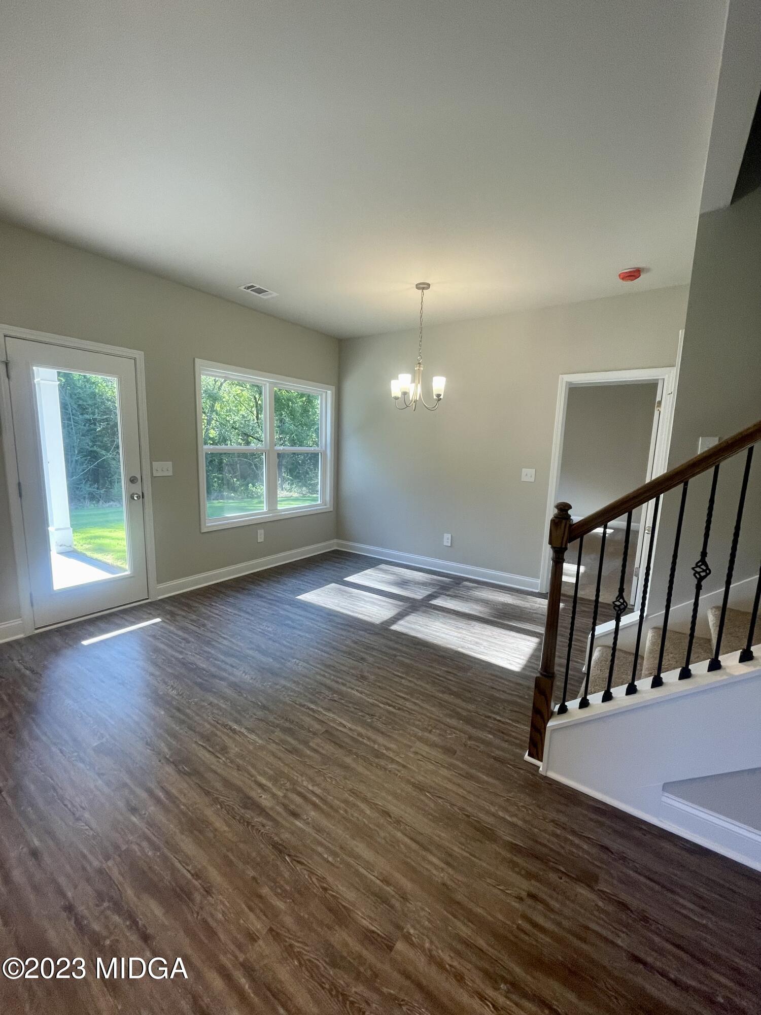 23 Strickland Loop Forsyth, GA 31029 - Photo 4 of 9 an empty room with wooden floor and windows
