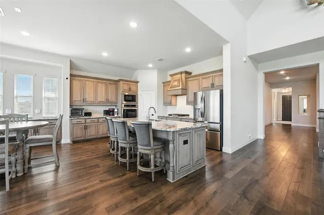 a kitchen with stainless steel appliances a dining table chairs stove refrigerator and cabinets