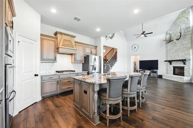 a kitchen with stainless steel appliances a stove a sink dishwasher a dining table and chairs with wooden floor