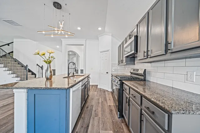a kitchen with granite countertop stainless steel appliances a sink stove top oven and cabinets