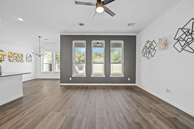 a view of an empty room with a window and wooden floor