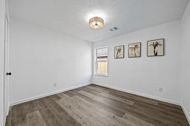 a view of empty room with wooden floor
