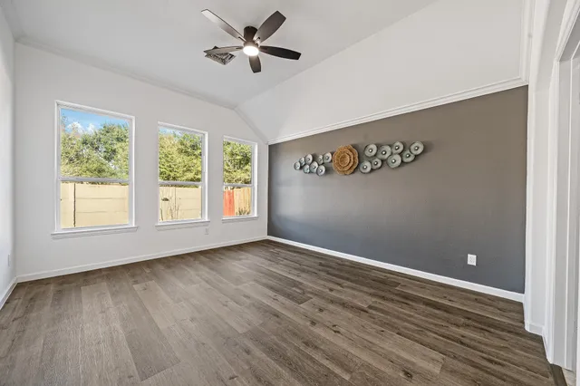 a view of an empty room with a window and wooden floor