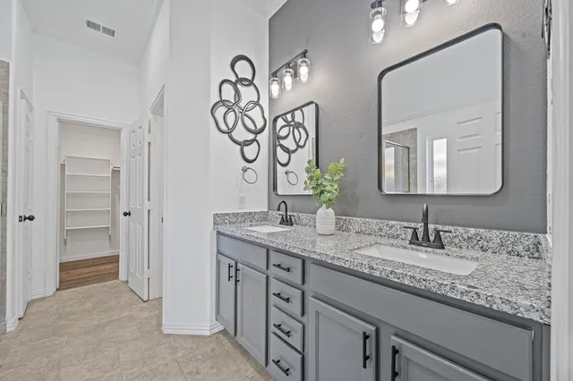 a bathroom with a granite countertop sink two mirror and a light fixture