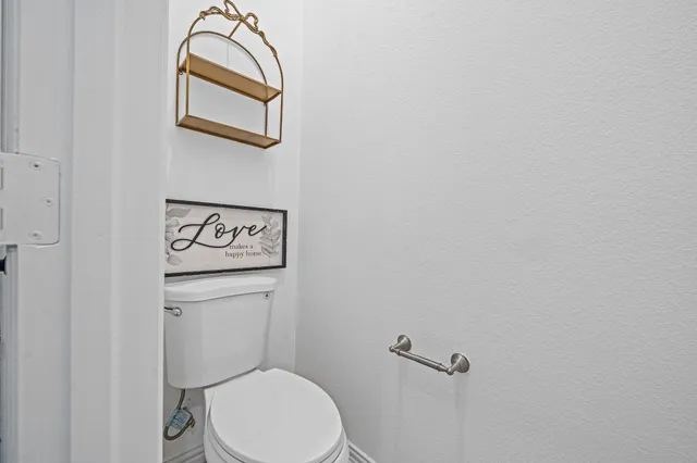 a white toilet sitting next to a white wall