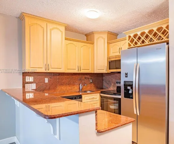 a kitchen with stainless steel appliances granite countertop a sink and a refrigerator