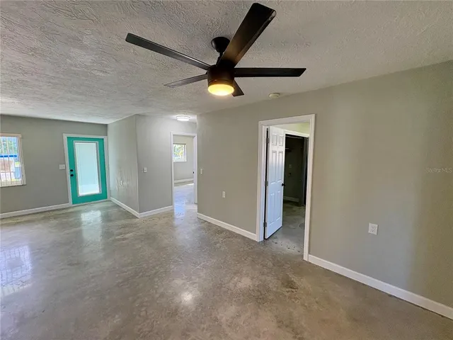 an empty room with ceiling fan and window