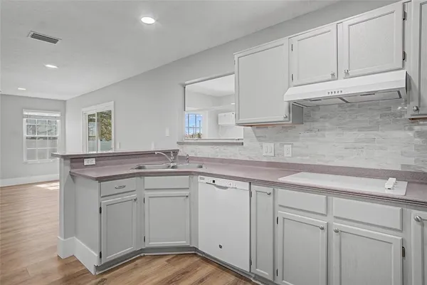 a kitchen with white cabinets and sink