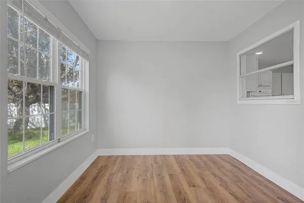 a view of an empty room with wooden floor and a window
