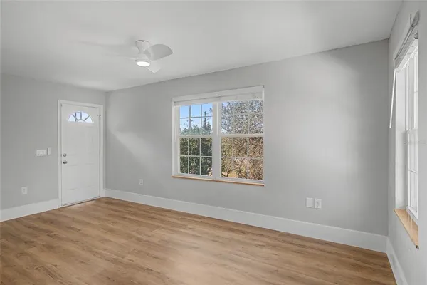 a view of an empty room with wooden floor and a window